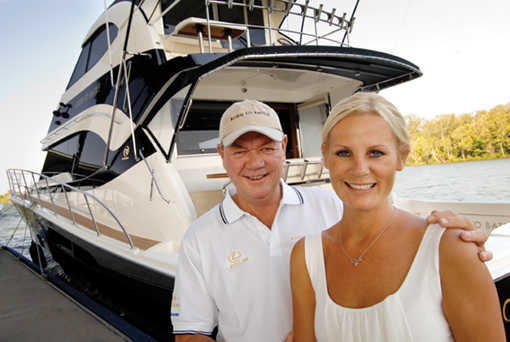 Peter Teakle and his partner Nina Mattingley in front of his Riviera 70 Flybridge Yacht 'Born to Battle'
