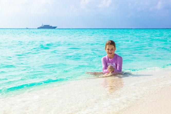 child on a beach and a yacht